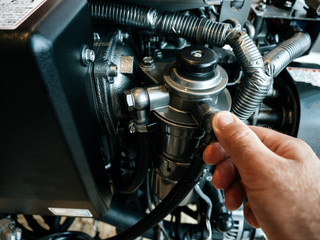 Young man hand repairing valve demonstrating the new 4-stroke, vertical, water-cooled diesel engine powerboat engine