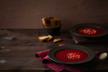 Healthy red beet soup or smoothie decorated with chopped pistachios and sour cream in the black plate in rustic style with copy space for text. Vegetarian lunch or dinner. Horizontal orientation