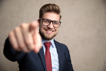 Wall Mural - Positive businessman pointing and laughing while wearing a blue suit