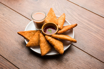 Poster - crispy Potato triangles or batata vada covered with bread crumbs and then deep fried. served with tomato ketchup. selective focus