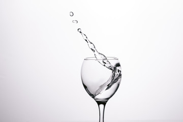 Wall Mural - splash of water in wineglass isolated on white background.