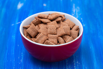 Sticker - Chocolate pillows in red bowl on blue wooden background