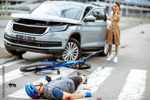 Fotografía Road accident with injured cyclist lying on the pedestrian crossing near the bro