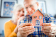 © leszekglasner - New house concept, happy senior couple holding small home model