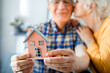 © leszekglasner - New house concept, happy senior couple holding small home model