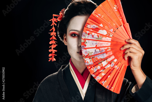 Fotomural attractive geisha in black kimono with flowers in hair holding bright hand fan i