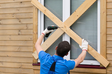 worker blocks the windows with boards to protect them from natural disasters