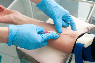 Wall Mural - Hand of nurse or doctor in blue gloves taking blood sample from a patient in the hospital.