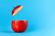 Health Red Cut Apple floating top slice juice drink idea concept on blue background