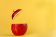 Healthy Red Cut Apple floating top slice juice drink idea concept on yellow background