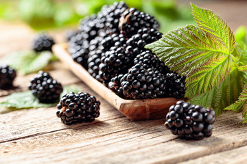 Wall Mural - Ripe juicy blackberries with leaves on a wooden table.