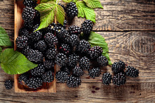 Ripe Juicy Blackberries With Leaves On A Wooden Table.