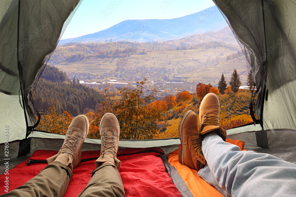 Closeup of people in camping tent with sleeping bags on mountain hill, view from inside - obrazy, fototapety, plakaty 