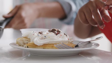 Wall Mural - Close Up Of Grandson Adding Sprinkles To Pancakes He Has Made With Grandfather In Kitchen 