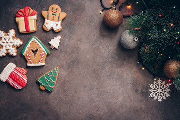 Wall Mural - Christmas festive composition with glazed gingerbread, pine, balls and garland on a dark rustic background. Top view, flat lay, copy space.