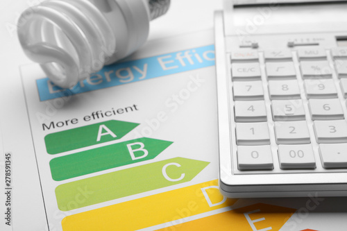 Fotografía Energy efficiency rating chart, fluorescent light bulb and calculator, closeup