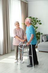 Canvas Print - Elderly woman and her husband with walking frame indoors