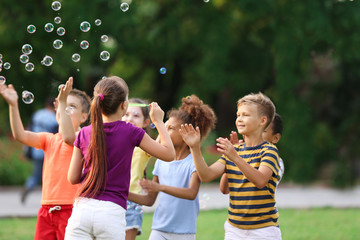 Sticker - Cute little children playing with soap bubbles in park