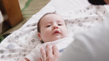 Wall Mural - Close Up Of Loving Father Playing With Newborn Baby Son Lying On Bed At Home In Loft Apartment