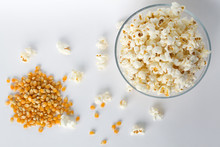 Popcorn In A Bowl With Yellow Corn Grains Isolated On White Top View