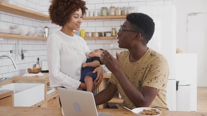 Wall Mural - Busy Family In Kitchen At Breakfast With Father Working On Laptop And Mother Caring For Baby Son