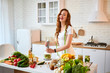 © bondvit - Young happy woman preparing tasty salad in the beautiful kitchen with green fresh ingredients indoors. Healthy food and Dieting concept. Loosing Weight