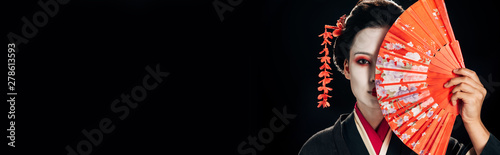 Cuadros en Lienzo attractive geisha in black kimono with flowers in hair holding bright hand fan i