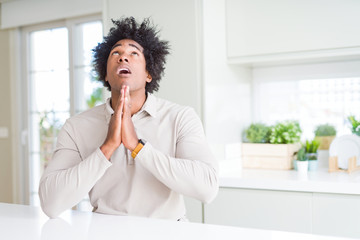 Sticker - African American man at home begging and praying with hands together with hope expression on face very emotional and worried. Asking for forgiveness. Religion concept.