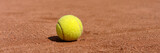Fototapeta  - yellow tennis ball on clay court, panoramic photo