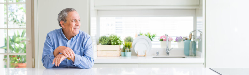 Sticker - Wide angle perspective of handsome senior man at home looking away to side with smile on face, natural expression. Laughing confident.