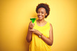 © Krakenimages.com - Young african american woman with afro hair drinking a cocktail over yellow isolated background with a happy face standing and smiling with a confident smile showing teeth