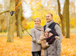 © Syda Productions - family, childhood, season, technology and people concept - happy family taking selfie with smartphone and monopod in autumn park