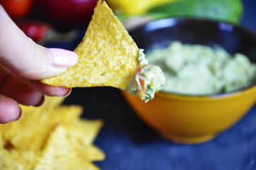 Mexican corn chips nachos with salsa dip on a black background with guacamole sauce, avacoda with lime and hot pepper