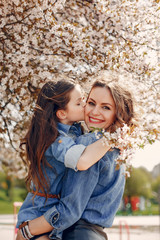 Fashionable mother with daughter. Family in a spring park. Woman in a blue shirt