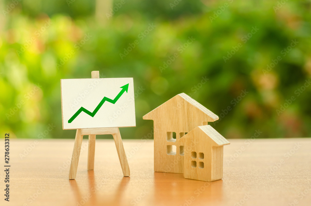 Two wooden houses and stand with green up arrow. Increasing cost and liquidity of real estate. Attractive investing. rising prices or renting. Apartments and apartments. Sales rate. Supply and demand