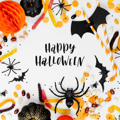 Canvas Print - Halloween holiday frame with colorful candy, bats, spiders, pumpkins and decoration on white background. Flat lay. View from above