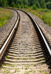 Railway turning left. Rails and sleepers on a background of green forest. The way forward.