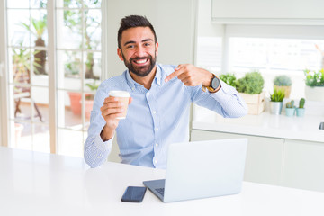 Poster - Handsome hispanic man working using computer laptop and drinking a cup of coffee very happy pointing with hand and finger