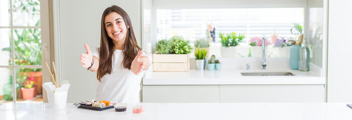 Poster - Wide angle picture of beautiful young woman eating asian sushi from delivery looking at the camera smiling with open arms for hug. Cheerful expression embracing happiness.