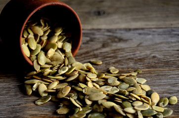 Peeled pumpkin seeds are scattered from wooden dishes on a wooden table ..