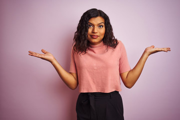 Wall Mural - Young beautiful transsexual transgender elegant woman over isolated pink background clueless and confused expression with arms and hands raised. Doubt concept.