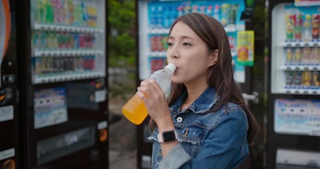 Wall Mural - Woman drink of bottle of orange juice in vending machine