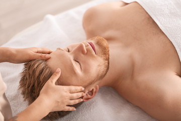 Handsome young man receiving massage in spa salon