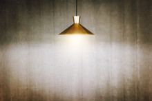 The Golden Lamp Hang On The Ceiling Is Shining With Old Concrete Wall Background