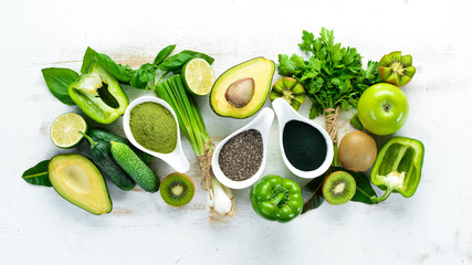 Wall Mural - Fresh green vegetables in a rustic white background. Avocado, kiwi, onion, lime, parsley. Organic food. Rustic style. Top view. Free space for text.