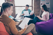 © deagreez - Profile side view of smart clever youth interns it specialists executive managers reviewing analytics financial documentation sitting on bag chair at industrial loft interior workplace workstation
