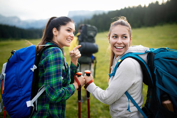 Wall Mural - adventure, travel, tourism, hike and people concept - group of smiling friends with backpacks and ma