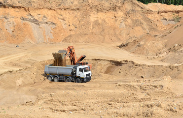 Poster - Excavator developing the sand on the opencast and loading it to the heavy dump truck. Processing of loose material in mining quarry. Drill, breaking, processing plant, crushing and screening  - Image