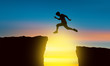 The silhouette of a man jumping over the abyss At the time of the sun set Concept of victory and success