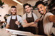 © Drobot Dean - Three cheerful men baristas standing behind the counter